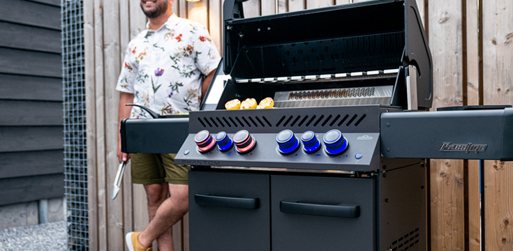 Napoleon Matt Black Phantom 500 Grill outside cooking with man standing next to the grill